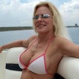 Pretty mature busty blonde woman in white bikini top on a boat.jpg