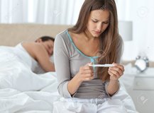 10218224-linda-mujer-mirando-un-test-de-embarazo-mientras-su-novio-durmiendo.jpg