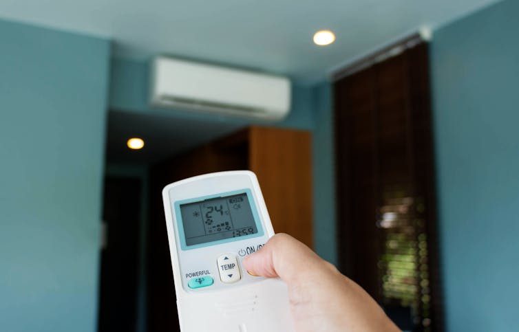 A person using a remote for their air conditioner