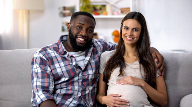 multiethnic-couple-looking-at-camera-pregnant-woman-holding-belly-ivf-picture-id1159252141